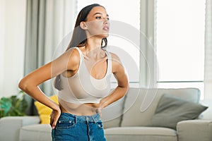 Slim caucasian woman doing belly vacuum abdominal exercise flexing muscles at home, free space