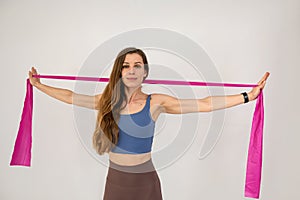 Slim caucasian woman during workout training muscles using rubber bands isolated on white
