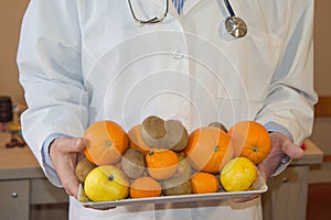 Slim down dieting concept. Doctor in white lab coat recommending healthy food. Doctor specialist dietitian holding fruit fruits an