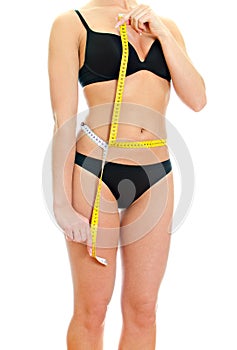 Slim female body with measure tape around waist.