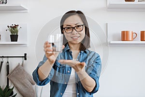 Slim female holding beverage in hand on kitchen background