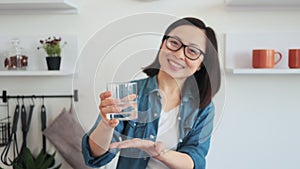 Slim female holding beverage in hand on kitchen background