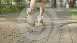 Slim female legs in high heels walking on sidewalk