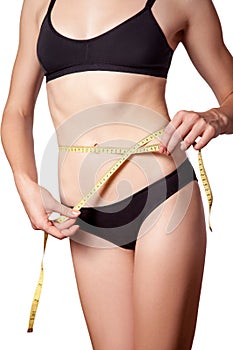 Slim fit happy young woman with measure tape measuring her waist with black underwear, isolated on white background.