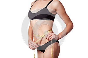Slim fit happy young woman with measure tape measuring her waist with black underwear, isolated on white background.