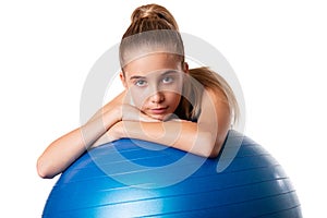 Slim and fit teen girl holding a swiss blue ball. Full length shot on white background