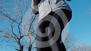 Slim fit young woman running or jogging over camera outdoors. Low angle view.