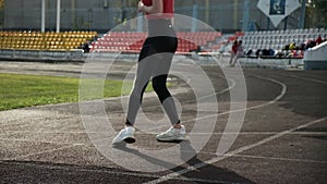 slim fitness runner in sportswear stands in starting position on stadium track