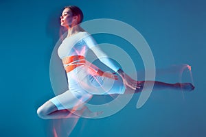 Slim flexible athletic young girl jumping. Graceful athlete ballerina flying in jump in air. Long exposure, motion blur