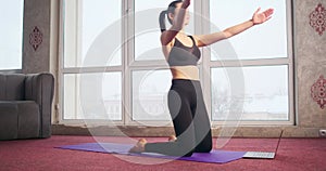 Slim, flexible girl practicing yoga, standing on knees, raising, bending, stretching.