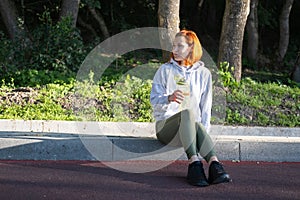 slim ginger woman runner in sport clothes sitting in park, drinking water. Healthy fitness lifestyle