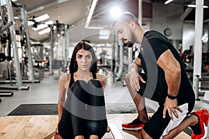 Slim girl dressed in black sports top and tights is doing exercises for the abdominals on the fitness mat in the gym