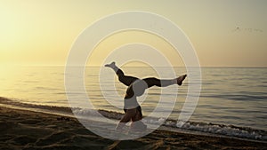 Slim girl keeping balance in headstanding outdoors. Yoga woman training on beach