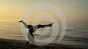 Slim girl keeping balance in headstanding outdoors. Yoga woman training on beach