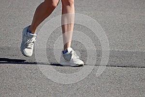 Slim girl running on a street, female legs in sneakers