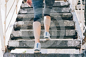 Slim girl in sneakers and sportswear climbing stairs, close-up