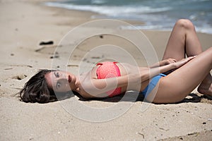 Slim girl wear bikini, lying on a sandy beach