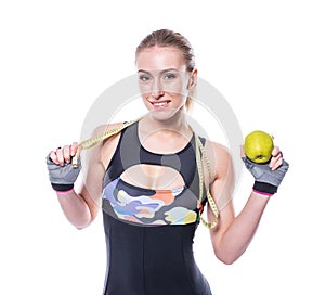 Slim and healthy young woman wearing sportswear tracksuit holding measure tape and green apple isolated on white background.