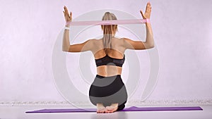 Slim lady fit coach making aerobics physical jerks for behind muscular body using stretch equipment