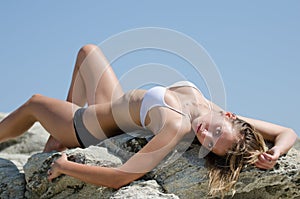 Slim lady with outstanding body lying on rocks and displays the body with admiration