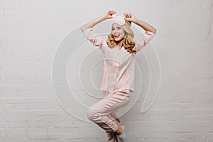 Slim lady in pink night-suit funny dancing isolated on white background. Studio shot of amazing fair-haired girl in cute