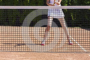 Slim legs of female tennis athlete behind fishnet