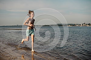 Slim long-haired man running along the river