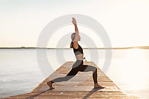 Slim Middle Aged Woman Practicing Yoga Outdoors, Making Warrior 1 Pose