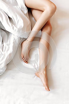 Slim, perfect and beautiful crossed woman legs on bed.