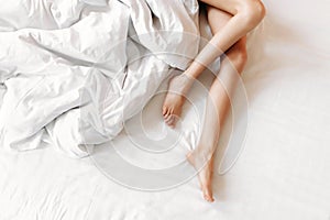 Slim, perfect and beautiful crossed woman legs on bed.