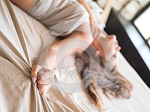 Slim, perfect and beautiful woamn on bed. Cropped image of erotically lying on bed beautiful woman in bedroom. Crumpled