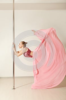 Slim poledance girl posing in beautiful pink dress