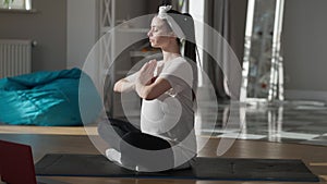 Slim pregnant confident woman meditating sitting in lotus pose on exercise mat. Side view wide shot beautiful Caucasian