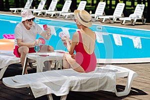 Slim retired woman wearing red swimming suit playing cards