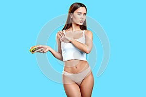 Slim sexy girl holding burger, doesn`t want to eat it as it has many callories photo