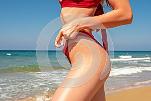 Slim sexy girl with a perfect figure in a red bikini on the beach. Fashion summer concept