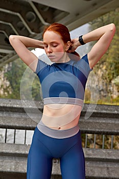 Slim slender fit caucasian female in sportive clothes preparing to run, doing ponytail