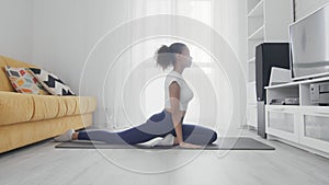 Slim sporty african american woman practicing yoga on a mat. Young woman doing yoga workout in room