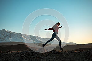 Slim sporty girl walks at sunset in mountains