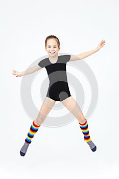 Slim teen girl doing gymnastics dance in jumping on white