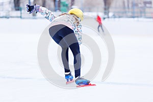 Slim teenage girl skating on the ice track on short treck training photo