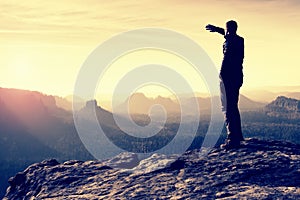 Slim tourist on the sharp peak of rock in rock empires park is watching over the misty and foggy valley to Sun