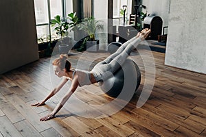 Slim woman balancing on stability exercise ball in fitness studio