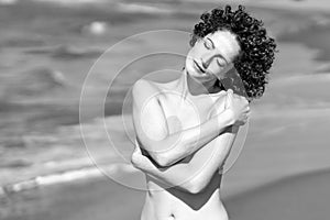 Slim woman in bikini standing on knees on sandy beach