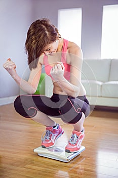 Slim woman cheering on scales