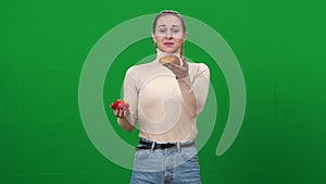 Slim woman choosing healthful apple holding fruit and bun in hands. Portrait of young Caucasian lady selecting food on