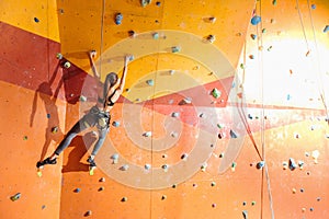 Slim woman climbing up special wall in gym