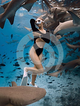Slim woman dives and posing with the shark in a tropical ocean in the Maldives