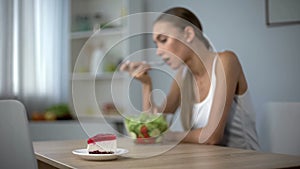 Slim woman eating healthy salad but dreaming about tasty cake, temptation