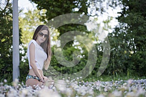 Slim woman facing the camera, chamomile field on foreground